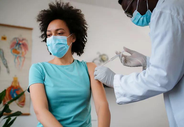 woman getting vaccine in arm at doctor's office