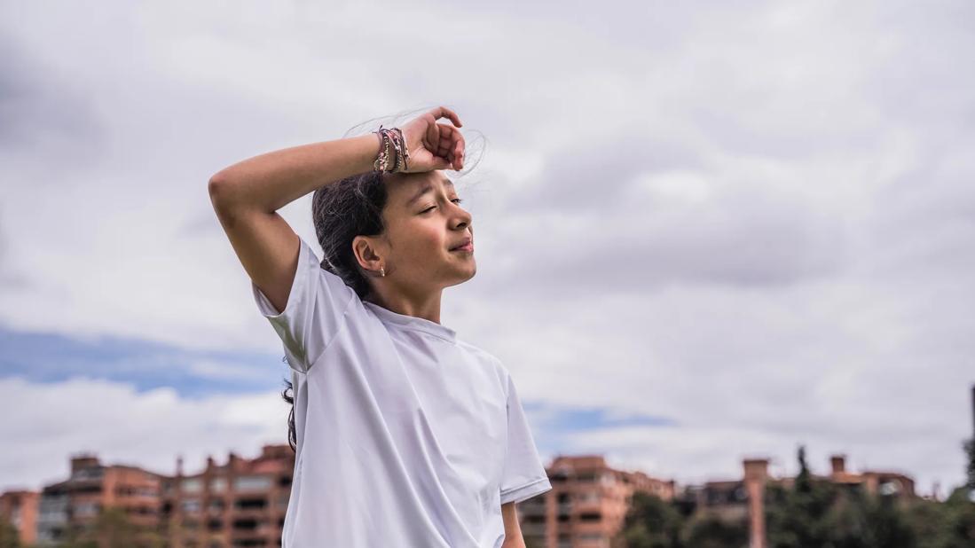 Kid outside on soccer field, wiping forehead