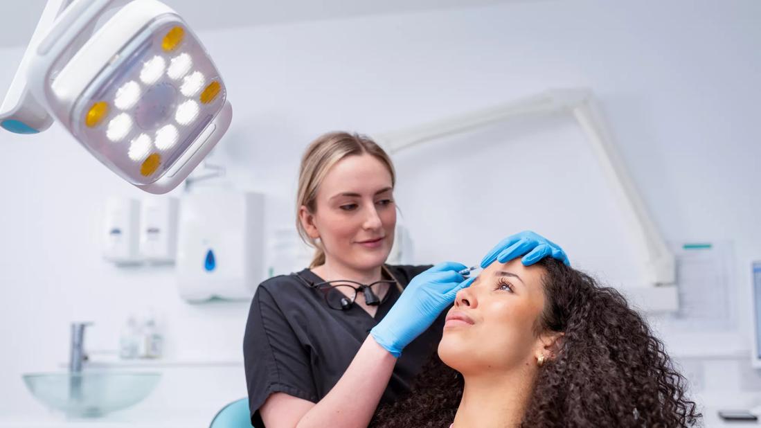 Younger person getting a botox injection in forehead from healthcare professional