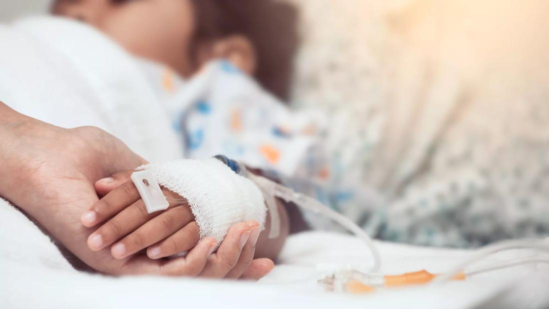 Caregiver holding child's hand after surgery