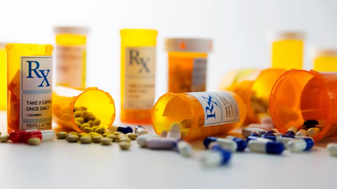 Assorted bottles of Rx medications with pills and capsules around