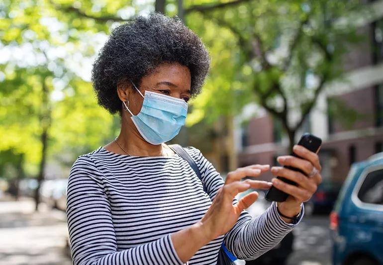 woman on street texting while wearing mask