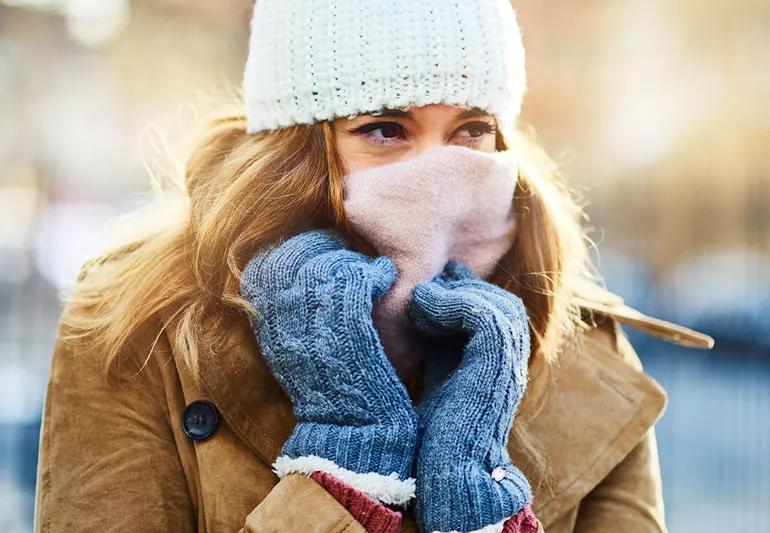 A person dressed for the cold weather in hat, scarf over face, gloves and coat