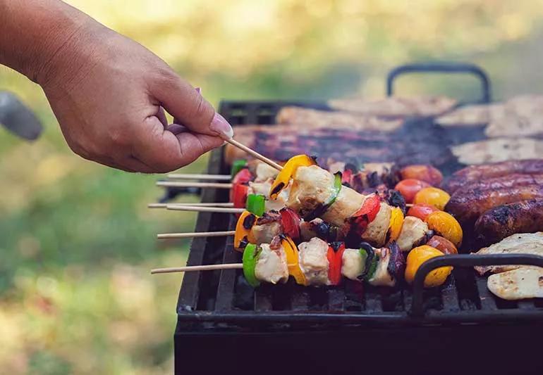 a grill with kebabs, sausages and chicken cooking on it