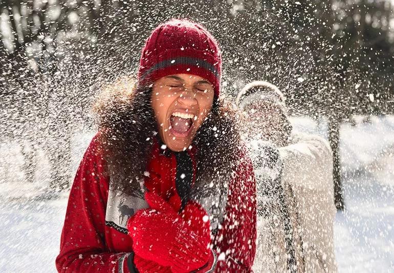 Laughing people participating in a snowball fight.