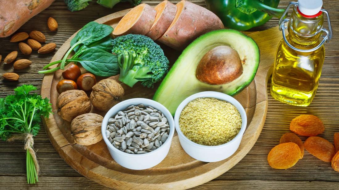 Foods rich in vitamin E: broccoli, avocado, sweet potato, almonds, sunflower seeds, apricots, pepper and a bottle of oil