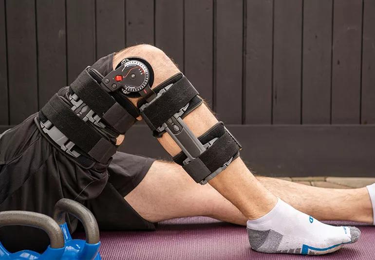 A person lying on a mat and wearing a knee brace