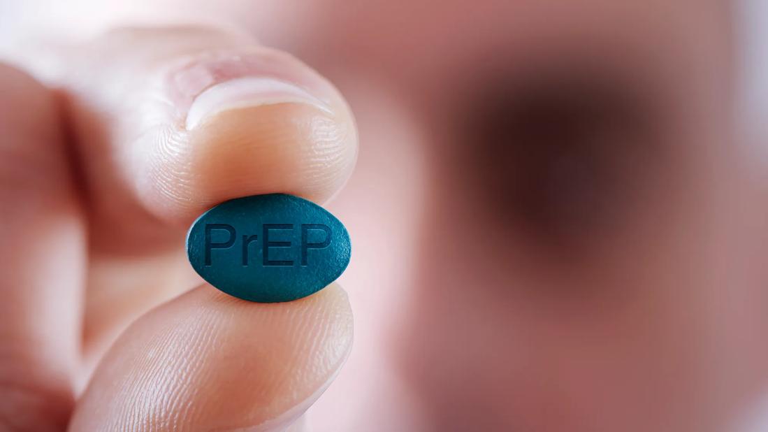 Hand holding blue PrEP pill