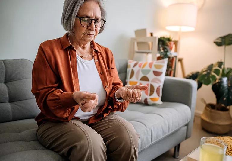 An older adult sitting on a couch making a fist with both hands