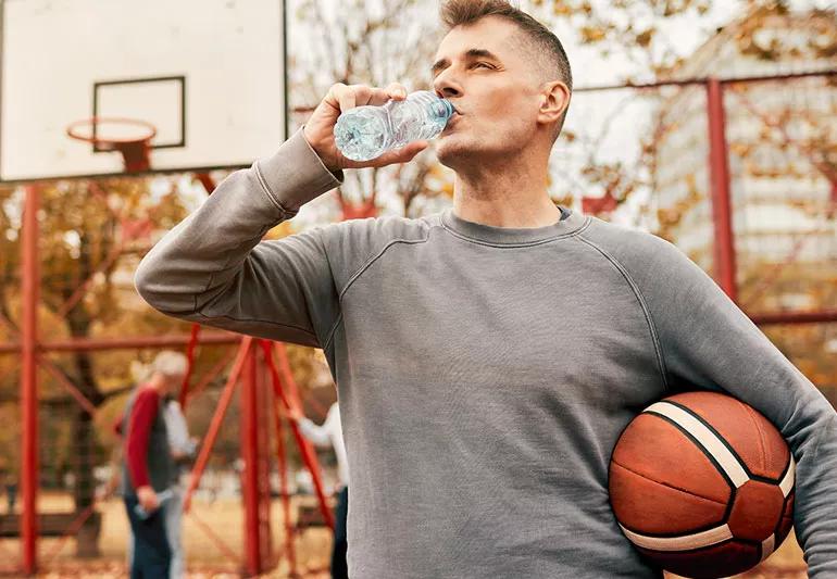 Man drinking water during break in basketball pickup game