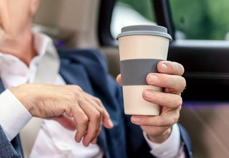 elderly man holding travel cup