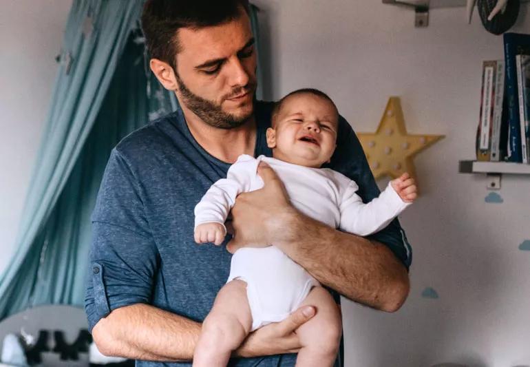 Father holding crying baby after feeding