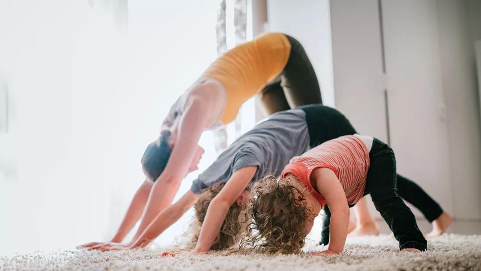 Parent and two children preforming downward dog in yoga