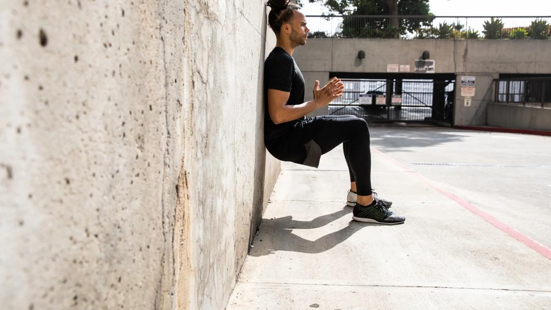 Person doing wall sits, or wall squats, outside