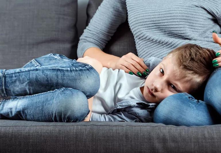 Small boy with upset stomach on couch with mother