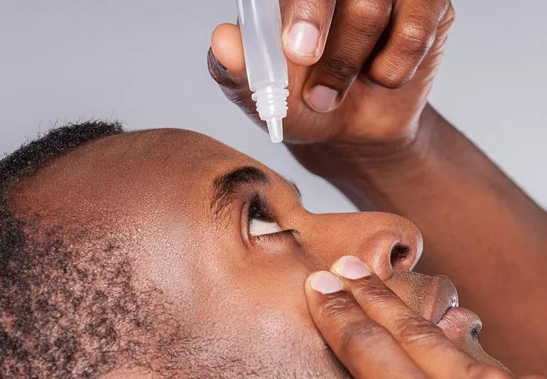 Closeup of a person using eye drops.