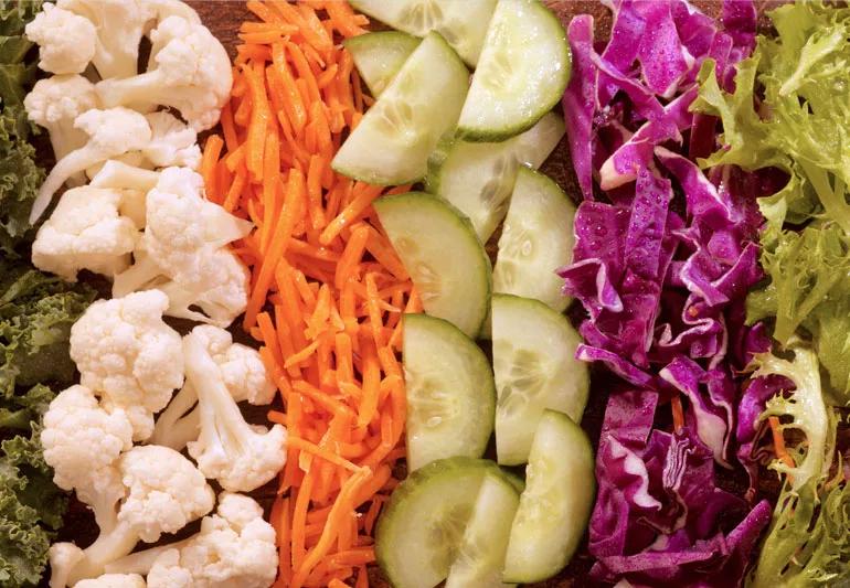 Closeup of precut vegetables including carrots cabbage cauliflower lettuce