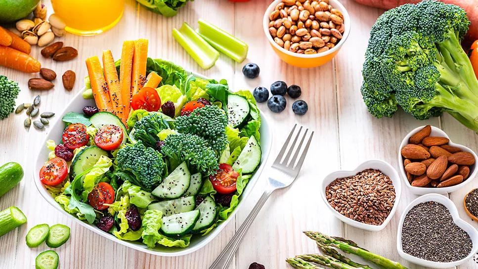 Colorful fruit, vegetables and nuts combined in bowl and scattered on table