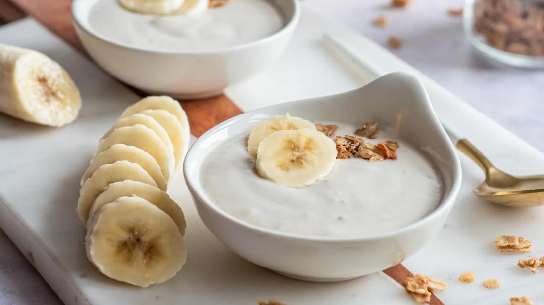 Two bowls of banana mouse on a tray with slices of banana