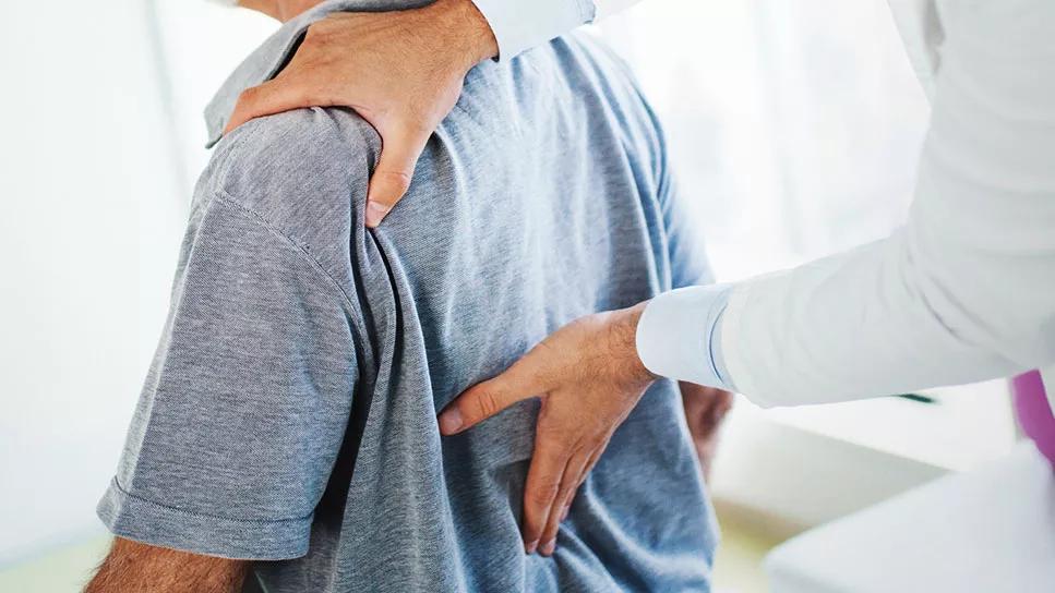 Patient at doctor office with physician checking their back
