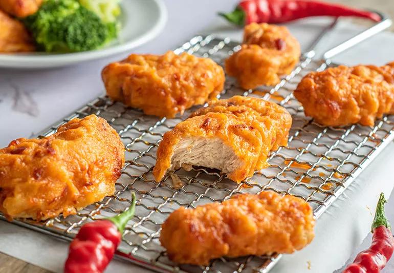 Baked boneless chicken strips coated in orange sauce on a cooling rack