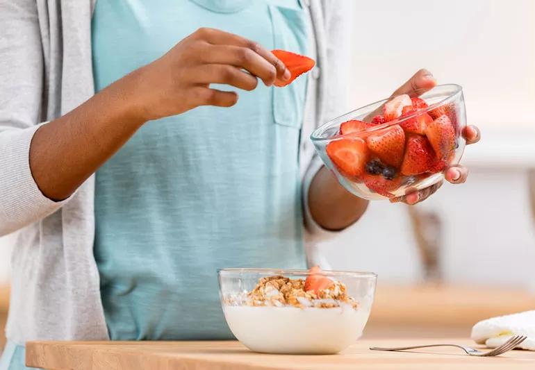 Woman preparing cereal with fresh fruit on top