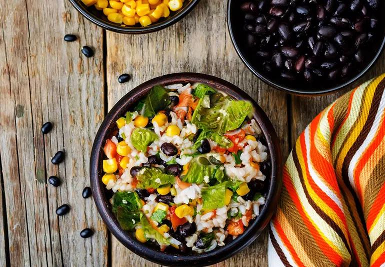 A salad containing rice, black beans, corn, tomatoes and romaine lettuce