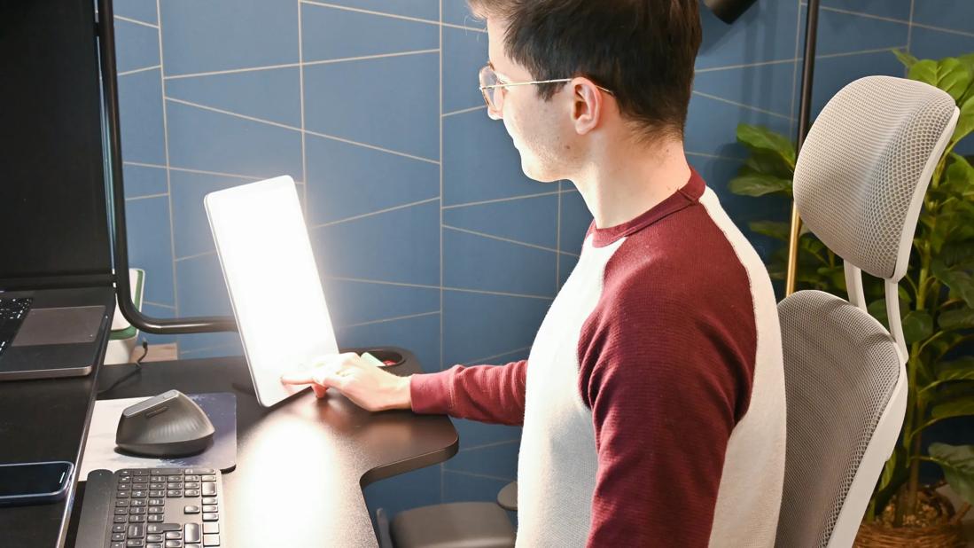 Person with a desk sun lamp facing them at their workstation