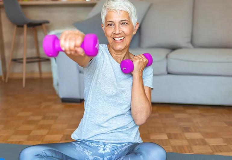 elderly woman lifts weights at home