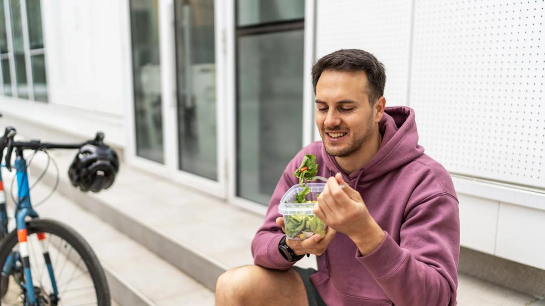 Person taking a break from bike riding, eating a salad