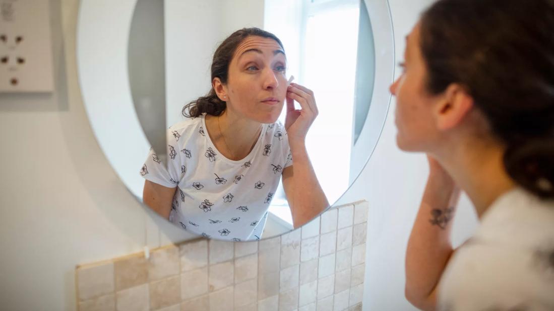 Person looking in mirror applying skin toner