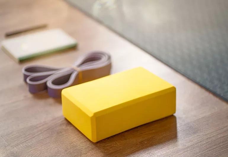 A yoga block and yoga strap laying on the floor.