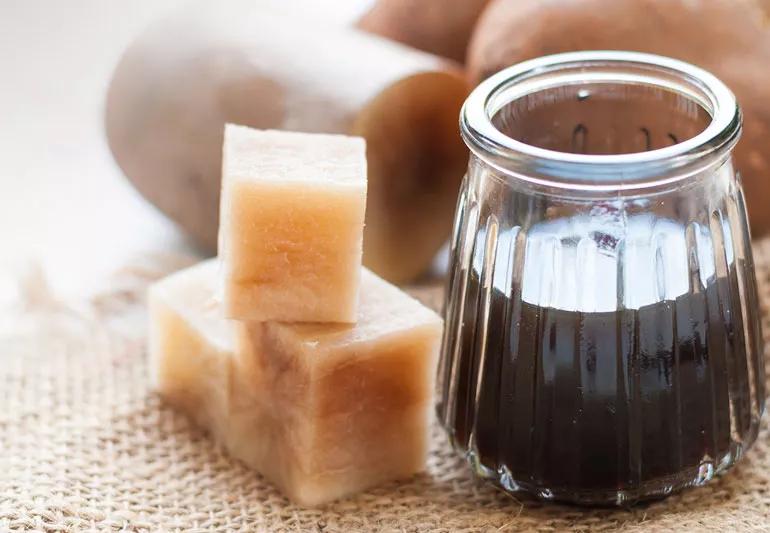 Yacon syrup in small glass jar displayed with yacon root all on a piece of burlap.