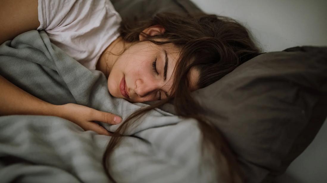 Tossled teen sleeping in bed, with pillow and blanket