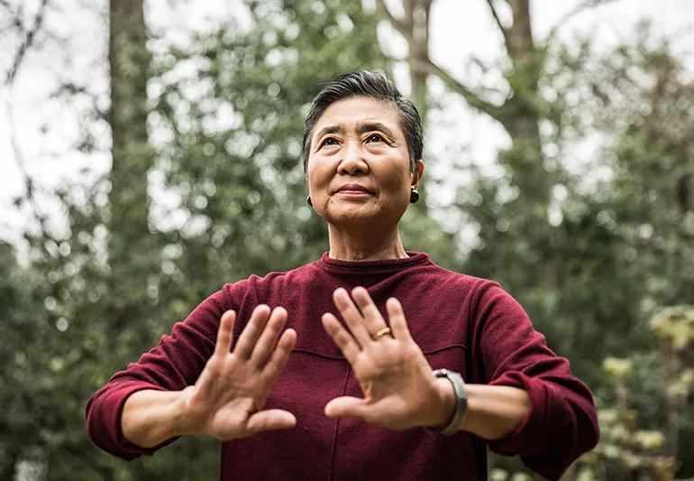 A person in the woods raising their hands in a meditation practice
