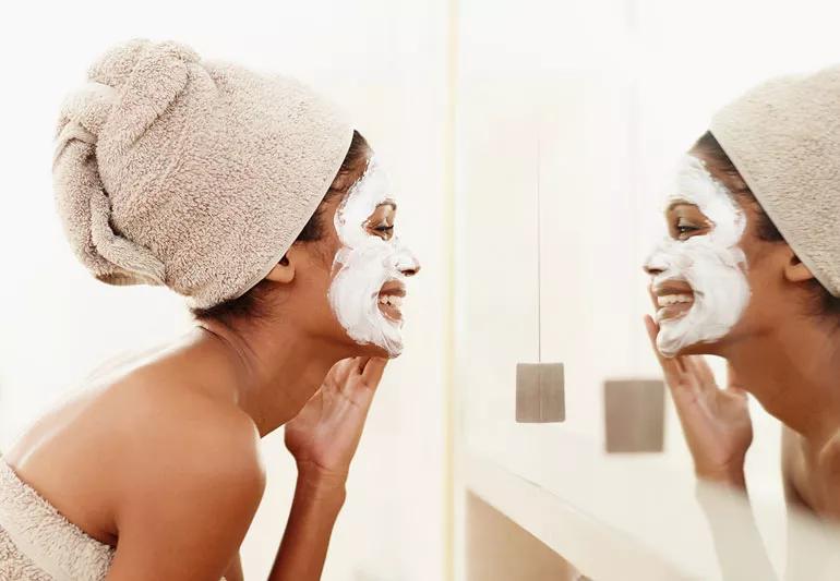 woman applying face mask in bathroom mirror