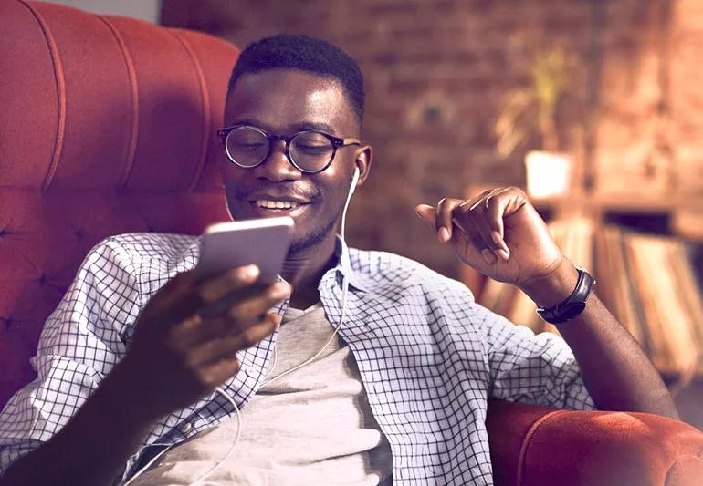 man with earbuds listens to music on his phone