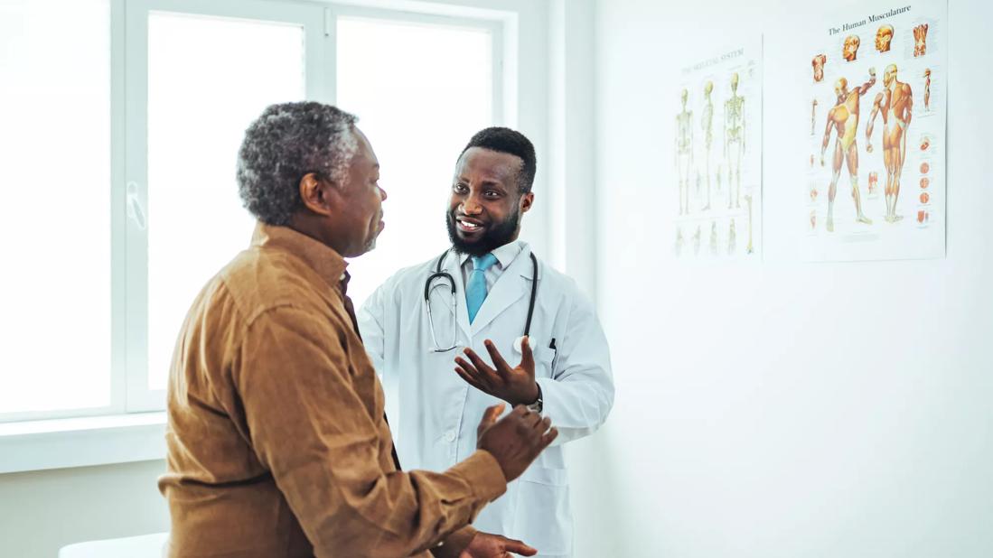 Healthcare provider consulting with male patient in exam room