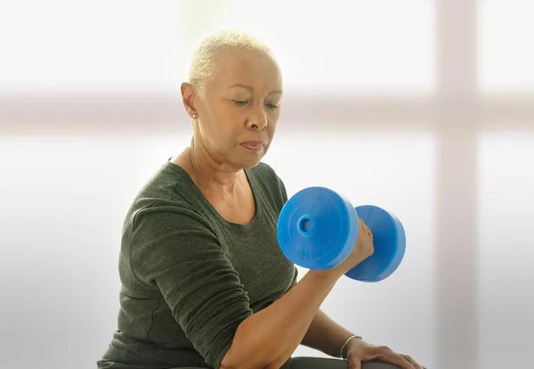 Elderly woman uses weights for strength training at home
