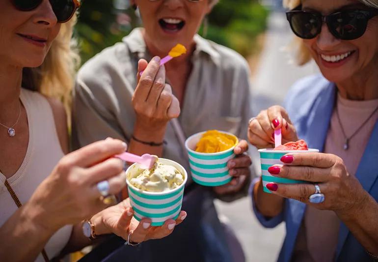 Elderly women eating cups of ice cream while out shopping