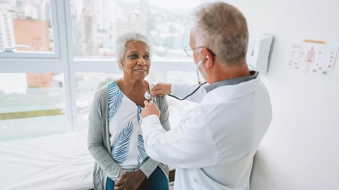Healthcare provider listening to a patient's heart with stethoscope in exam room