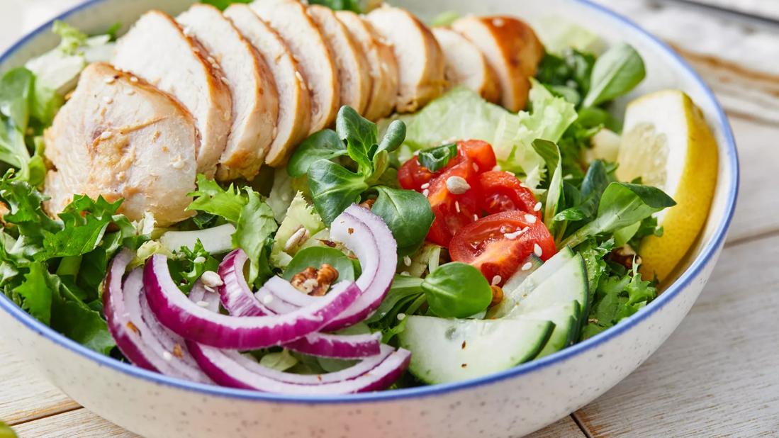 Sliced grilled chicken over salad