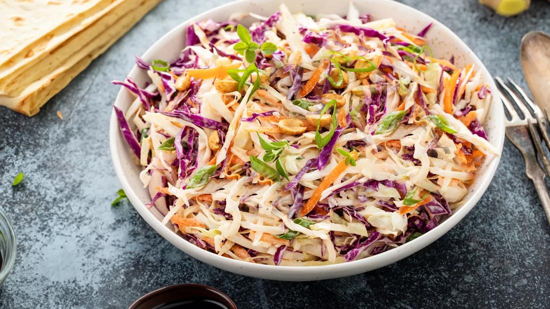 Bowl of Asian chicken slaw mixture with stacked tortillas, ginger and hoisin sauce