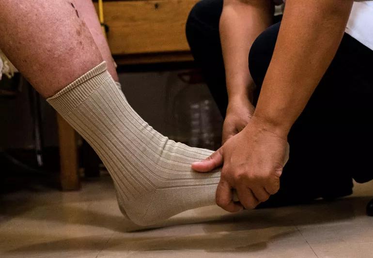 Nurse checks elderly man's foot