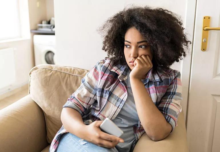 Young woman sad sitting on couch