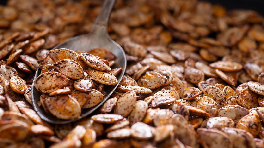 Spoonful of pumpkin seeds on a bed of roasted pumpkin seeds