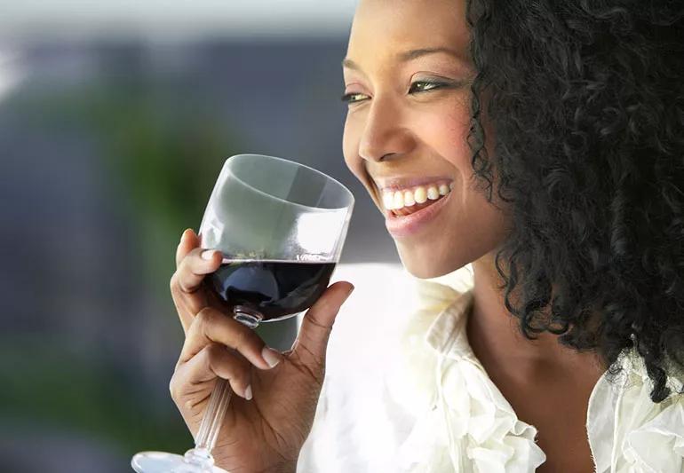 Closeup of a happy person drinking red wine.