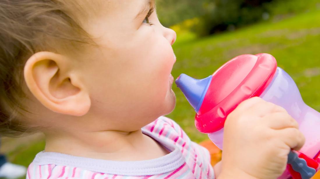 Happy toddler holding sippy cup