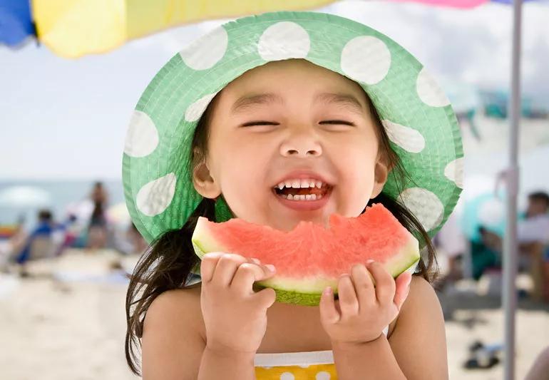 happy girl eating watermelon at the beach