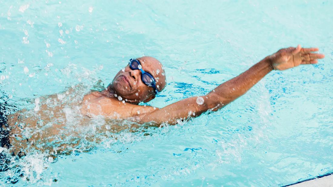 Person wearing goggles doing the back stroke in a pool